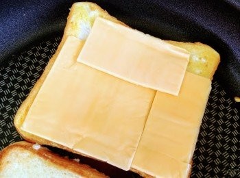 step5: 待麵包煎出蛋香味後，反轉；迅速將芝士放於蛋汁的一面，蓋上另一片煎好的麵包，即牛油的兩面向外，蛋汁的兩面向芝士。通常片裝芝士比麵包小，所以會用兩片芝士鋪滿麵包，當然，可以用上芝士碎或者多片芝士。