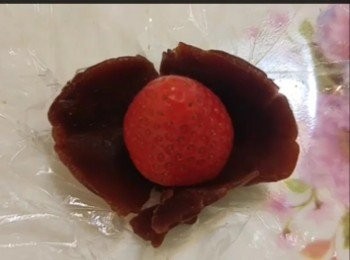 step2: ~把紅豆茸分成22g10份，每搓圓後放在保鮮紙中用掌心壓扁，放上一粒尖向頂的士多啤梨，利用保鮮紙把紅豆茸包裏全粒士多啤梨，完成後雪進冰箱雪15-20分鐘至稍硬（切勿過久）；