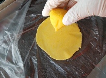 step28: 當皮雪硬身後要搓皮時，取出用一個食物袋，將食物袋剪開一邊，打開一邊袋放入一塊皮,夾住塊皮搓闊先包餡(用食物袋更易操作) 將餡尖位向下(尖位是多奶皇餡放底部,作用是妨止流沙餡不易流出外)