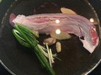 step3: 取一深鍋，放入小牛腱、蔥、薑和蒜，加入足量淹沒小牛腱的水量，倒入米酒；大火煮滾後轉小火慢煮1小時；