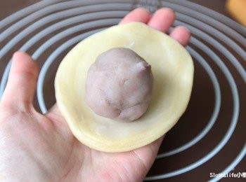 step11: 先稍微用手掌壓平後，再使用擀麵棍將周圍捍出約2公分後，放入<span class="group_1">芋泥球</span>，餅皮往內收口捏緊，注意不要壓到紋路。