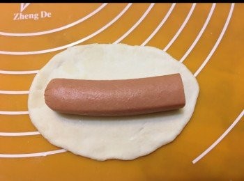 step3: 一條廚師腸大約13 cm長，我用4條廚師腸，每條分三段總供12段。首先將腸仔用刀切開大約四cm，用9cm長腸仔放上麵團包好待用，剩餘的4cm腸仔再加上另一條4cm腸仔放在麵團上包好待用。（扭扭團部份，可因喜好自行調教腸仔長短）