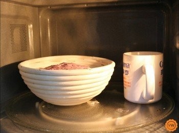 step6: 發酵籃抹上一層厚厚的高筋麵粉，再麵糰整型成圓後，以收口朝上的方式放入發酵籃內，再放到微波爐進行第二次發酵，可以在微波爐內放至一杯熱水來提升理想的發酵環境。