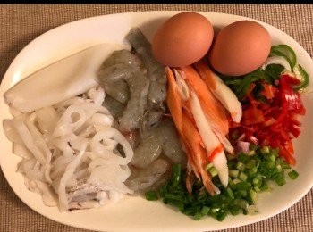 step1: 首先將蝦和魷魚下鍋汆燙至水滾後取出，瀝乾水分備用。蟹柳解凍後，撕開成絲狀。

少許紅、青辣椒：切絲，3湯匙蔥粒及2隻蛋。