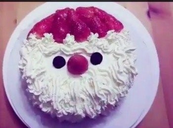 step7: 調溫朱古力，座溶後在牛油紙上畫出兩個圓形作眼睛及一個微笑型，待涼後，放上蛋糕上做出聖誕老人的樣子 及在士多啤梨聖誕帽上加上聖誕金球