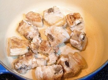 step2: 在鑄鐵鍋中放一湯匙油, 燒熱後將一字排逐件放入, 以中火兩面煎三、四分鐘至微焦後取出, 倒入薑片和蒜頭炒香, 除了冰糖, 將已混合好的<span class="group_2">調味料一</span>倒入鍋中