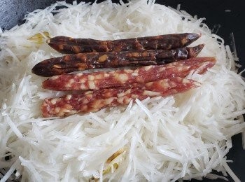 step5: 少少油爆香薑片，放入蘿蔔條，面放臘腸，鴨膶腸，焗煮15分鐘，之後將臘腸，鴨膶腸，薑片取出，(這樣蒸煮臘腸，鴨膶腸，是將油份及味道滲透落蘿蔔內