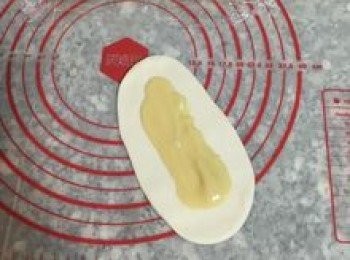 step15: 從第一顆揉圓的麵糰開始桿，用桿麵棍將麵糰桿成牛舌狀，並用湯匙在中間抹上<span class="group_3">油酥</span>，四週都要留空間不要抹到，尾端那頭要特別留多一點，方便等一下的黏合。