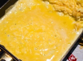 step14: 再倒入1/3的蛋液。
重複之前的步驟，攪拌蛋液。
遇到泡泡就搓破，並搖晃一下讓蛋液留進去填補。
＊泡泡一定要搓破喔，不然蛋捲就不會綿密了！
最後捲起並推至頂部。