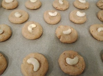 step8: Press one raw cashew nut in the middle of each cookie, brush the top of the cookies and cashew nuts with the remaining egg.