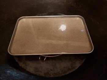 step5: 準備蒸煮工具，開大火煮滾水，準備 2個平的糕盆交替使用容器表面用少許油掃面，用廚房紙抹勻倒入， 1湯勺的芝麻漿，搖勻至厚薄一致。大火蒸3分鐘