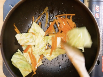 step2: 在炒鍋裡倒入麻油，大火放入紅蘿蔔翻炒。
接著加入高麗菜，繼續翻炒。