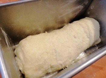 step5: 捲成條狀，在面洒上芝士粉，焗爐預熱180度1分鐘，然後關上焗爐電掣，焗盤塗上少許油及洒上麵粉，把多餘麵粉倒出，放麵團入焗盤內，入爐發酵1.5小時後會膨脹至2倍大如圖