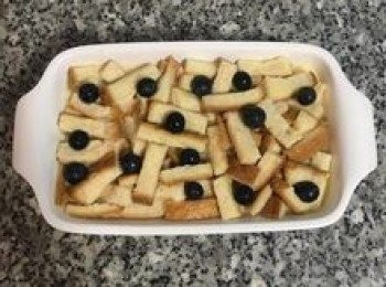 step9: 和剩下的藍莓，並均勻倒入布丁液，用湯匙略壓，讓上面的吐司邊也沾到布丁液；
將烤箱加熱到170度。