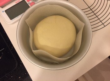 step3: 枱上灑上高筋麵粉，將第一次發酵完成的麵團空氣拍出，滾圓，修口向下，放在已鋪上牛油紙的模具內，在麵團上噴些少水，蓋上保鮮紙，放入密閉空間發酵約50分鐘至兩倍大