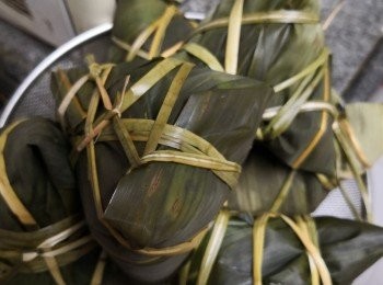 step4: 用兩片葉修剪頭尾對疊成三角形 然後放入糯米 中間放入餡料然後再用糯米，捏成4角將竹葉摺實包好用鹹水草扎穩打結