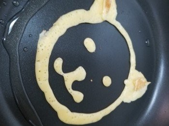 step2: 吾好開火先塗上油，首先搖一搖粉漿膠樽， 
唧出決定熱香餅大小的圓線，
再在圓線左右兩角上唧上2個小三角形做喵咪耳朵，
再唧上眼睛2圓形+鼻子小橢圓形+嘴巴w形，
唧完開中火煎1分鐘