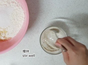 step14: 另一個大杯裡放入2湯匙依士、1/2湯匙糖和53ml牛奶後拌勻。