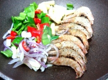 step6: 再加入少少黑椒+胡椒粉灑在蝦上面，
加埋洋蔥絲+蒜片+乾蔥片+青紅椒塊+粟米芯落鑊炒香，