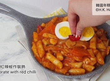 step12: 在炒年糕上加上烚雞蛋，加上紅辣椒和灑少許芝麻作裝飾，完成。