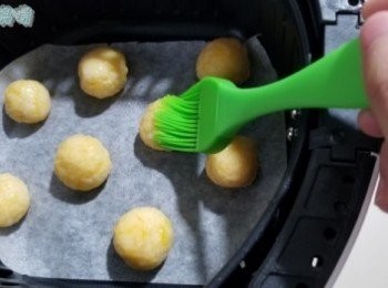 step3: 將粉團壓扁，並放入芝士粒，再慢慢包好，備用。 將煮食紙放係免油健炸寶嘅籃內，再以油掃輕輕於煮食紙上掃少少橄欖油， 將芝士波波放置於煮食紙上，並於芝士波波掃少少橄欖油