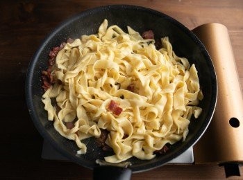 step9: 將步驟7煮好的<span class="group_1">麵條</span>與少許的煮麵水倒入培根中拌炒均勻，接著離火靜置約60秒。