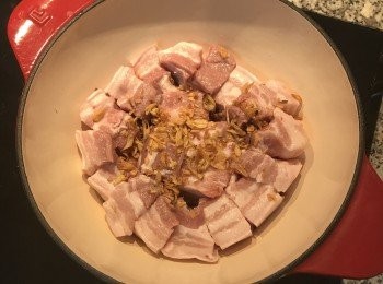 step3: 取鑄鐵鍋，在鍋裡放一半的紅蔥酥，擺入豬肉，再撒上剩下的紅蔥酥；開小火熱鍋！