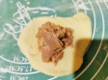 step1: 先將所有材料放入麵包機製作麵糰，大概1小時後取出。把麵糰分8份，滾圓後壓平排氣，把一罐油浸吞拿魚開後取出來再放入壓平了的麵糰上。