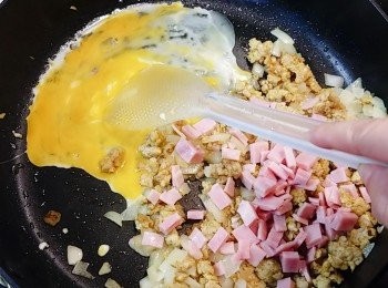 step3: 加入蒜蓉和火腿粒略炒，跟著調最小火，在鑊邊旁打入一隻雞蛋，將蛋炒散至碎粒。