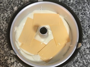 step11: 接著再倒1/3的蛋糕糊入模具中略微抹平；再將剩下的起司片,排在第二層的蛋糕糊上；