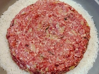 step6: 開大火煮米飯，期間需不時攪動米粒，煮滾後，轉細火煮5-7分鐘左右，見水份已被煮至差不多蒸發，此時將牛肉餅放在飯上，開大火煮1分鐘後，再轉超細火煮約10分鐘，熄火焗10分鐘至肉餅熟。