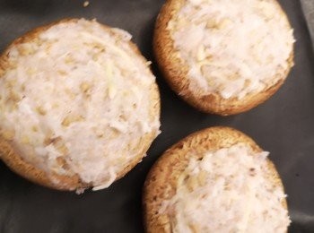step2: 大啡菇放入牛油蒜蓉，再釀入大啡菇蝦滑餡料，面放上少許芝士碎，大啡菇放入烤焗淺盤。