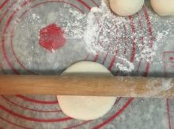 step13: 工作台和桿麵棍上撒些手粉；便可開始桿包子皮，取第一顆捏好的圓麵糰，手掌壓扁後，桿麵棍從中間交差桿ㄧ下，這是要桿出包子皮的厚度；