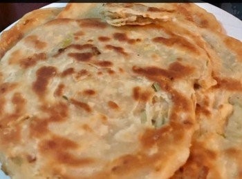 step5: 用一個平底鍋，下油熱鍋以中火將麵糰慢慢放入，一面煎至金黃色後，翻面煎另一面，油多一點煎出來會脆口。 以廚房紙或吸油紙吸走多餘的油，可用剪刀或刀將蔥油餅剪成三角形，然後裝盤即可。