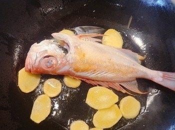 step3: 燒熱鑊，下油約兩湯匙，油滾後下薑片(因我家人很怕魚腥味，所以我用較多薑片)。爆香，將大眼雞魚放入鑊中煎封，兩面各煎1分鐘便可，取出備用。