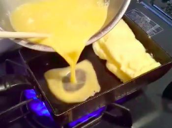 step7: 再倒入剩下的蛋液1/3。同時擡起一點剛才卷好的蛋卷，讓蛋液流到蛋卷底下。 再 一層一層地卷起来。