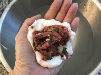 step12: 待粉漿完全降溫後，準備ㄧ大鍋水，將手浸濕；取適量粉糊，放在手掌上壓扁，擺上肉餡；