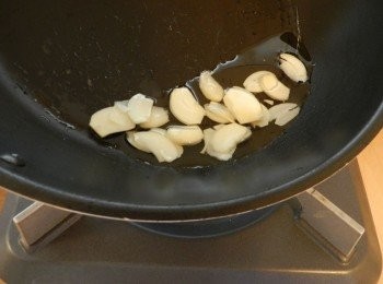 step3: 在平底鍋中加入（C)沙拉油和蒜頭切片，以中火加熱。