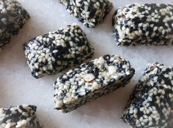 step2: 在鍋內加入麥芽糖、糖和水，用中火煮至糖溫度至125-130度C，然後立刻離火（*如沒有溫度計，可煮糖至沸騰，有大氣泡出現，然後將一滴糖漿滴落一碗水內，如果糖漿立刻凝固和硬身，就代表OK）

倒入芝麻和果仁，快速拌勻，然後倒在烘焙紙上. 再用擀麵棒擀平表面，待數分鐘，然後趁還是熱時，將芝麻糖切件(*因為如果涼了，很難切開和會碎）