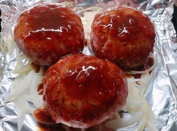 step6: 預熱焗爐200度，焗盤上鋪上錫紙，將洋蔥絲平均地放在錫紙上，放上漢堡扒再淋上醬汁。(亦可將漢堡扒先煎封兩面的表面才放入焗爐內也可，賣相更佳。但我懶沒有煎封。haha~)
