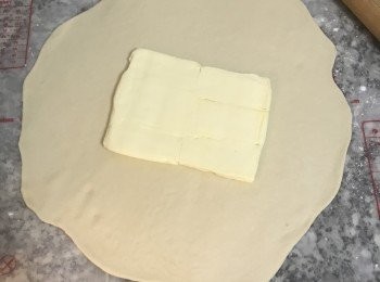 step8: 工作台上撒些手粉；將麵糰桿成圓方型；冰箱拿出奶油，除去保鮮膜，將奶油放在麵皮中間；
