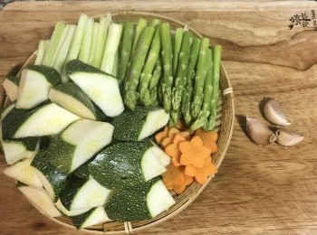 step1: 蘆筍洗淨，用手折的方式將蘆筍較嫩的部份折下，並且用刨絲刀將較嫩部位的靠近斷口部位的皮輕輕的刨掉。再把折斷後較粗的另一半的尾端切除不要。剩下的部份同樣的用刨刀將皮刨掉後洗淨。櫛瓜洗淨滾刀切塊，紅蘿蔔可切片或用模型壓出花樣。
