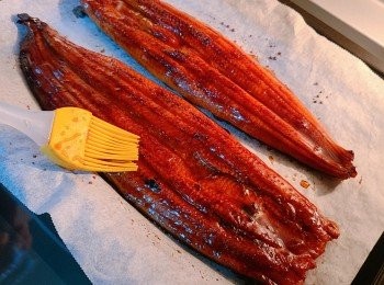 step3: 先預熱焗爐180度，鰻魚放在鋪了烘培紙的焗盤上，每條鰻魚各先加入1湯匙清酒讓其吸收，入爐前再均勻地塗上蒲燒鰻魚汁 ，全程焗約 8 至 10分鐘，其間再均勻地塗上多一次蒲燒鰻魚汁。出爐後切件，放在煮好的滑蛋和白飯上面便可。完成後可撒上些芝麻或紫菜碎也可。