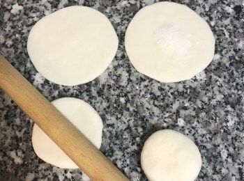 step15: 工作台和桿麵棍上撒些手粉；便可開始桿<span class="group_4">包子皮</span>，取第一顆捏好的圓麵糰，手掌壓扁後，桿麵棍從中間交差桿ㄧ下，這是要桿出<span class="group_4">包子皮</span>的厚度；接著再延著麵糰邊緣，先往內推桿再往外壓桿出來；整圈都桿壓過2-3次後即成中間較厚的<span class="group_4">包子皮</span>；