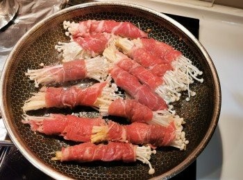 step2: 然後放油到平板鑊，將每條包好的金菇牛肉卷封口向下。目的是先將收口煎熟，那牛肉卷會無咁容易散開。