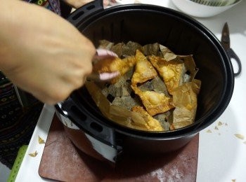 step9: 準備一片焗爐紙，摺疊後剪四角成洞洞焗爐紙
氣炸鍋先180度預熱 5分鐘
先墊上焗爐紙，再放上雲吞，噴一點點油
入氣炸鍋180度5分鐘即成