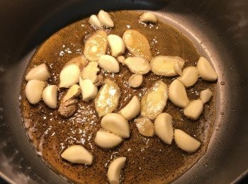 step6: 深鍋加熱後，放入黑麻油和橄欖油，放入薑片和蒜頭，溫火炒香；