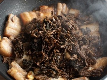 step5: 接著醬油、米酒與步驟1的梅乾菜拌炒後，加入開水煨煮約45分鐘。