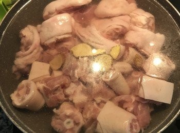 step3: 大鍋中放入豬腳、豬尾巴加滿冷水，薑3-4片，米酒少許，小火煮出雜質。