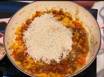 step7: 加入辣肉腸粒和小甜椒粒，中火拌炒3分鐘，加入西班牙米拌炒均勻